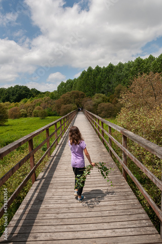 Una niña pasea por la pasarela de madera de la Laguna de Cospeito