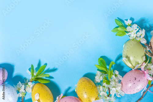 Happy Easter Spring Holiday Greeting Card Background with Easter colorful eggs, decorative bird nests and blossom spring garden flowers, flatlay copy space on wooden white background photo