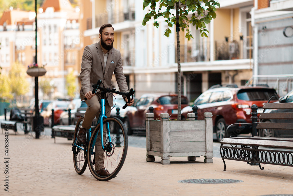 Fototapeta premium A businessman with a beard and in a suit rides a bicycle to work. Eco-friendly mode of transport, active lifestyle.