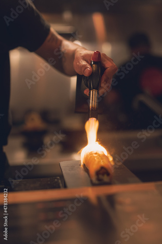Persona con soplete caramelizando un trozo de pescado