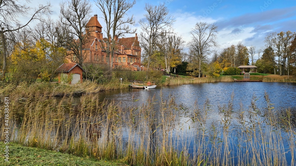 Fototapeta premium Beautiful old Latvian castle Jaunmoku among trees with yellowed leaves October 16, 2021