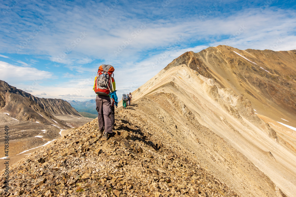 A group of hikers on a narrow ridge line in Alaska's Northern Talkeetna Mountains.
