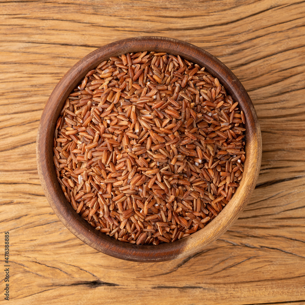 Raw red rice in a bowl over wooden table