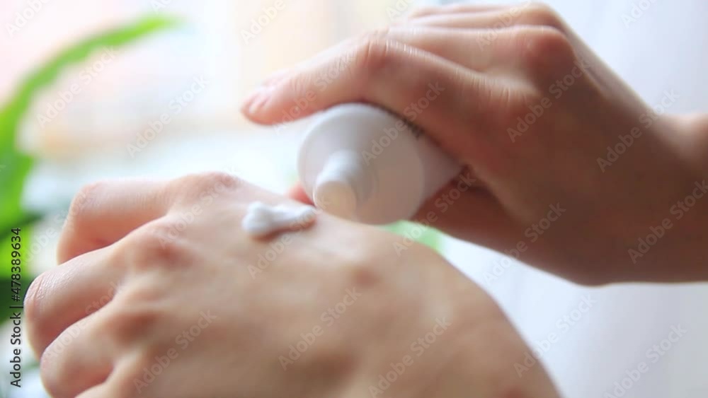 a woman's hand applies cream from a tube to her hand and rubs it. a woman's hand applies cream from a tube to her hand and rubs it.