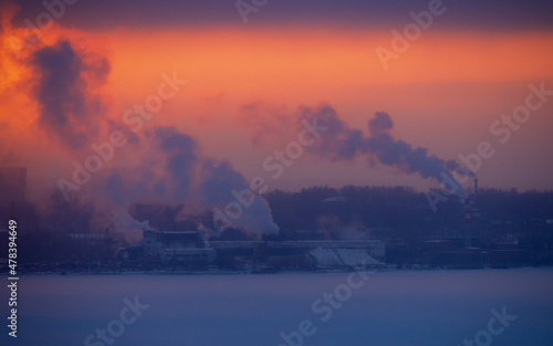 Chimneys smoke in winter against the background of the city and the sky.