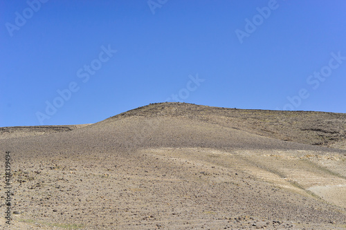 Stone Desert on the West Bank. Judean Desert in clear weather. White sand dunes and blue sky. Stony desert in the spring, green grass. Sand Hills of Judean Mountain, Israel. 