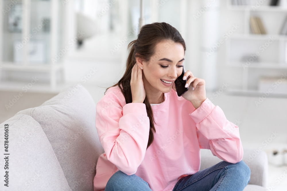 Happy woman talking on mobile phone sitting on comfortable couch Happy woman talking on mobile phone sitting on comfortable couch