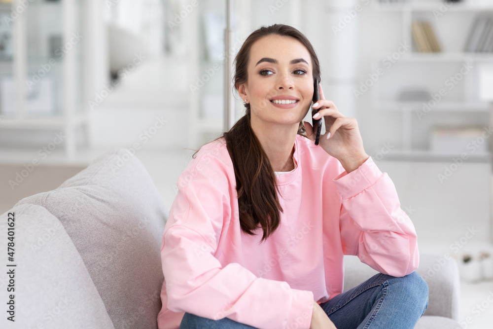 Happy woman talking on mobile phone sitting on comfortable couch Happy woman talking on mobile phone sitting on comfortable couch
