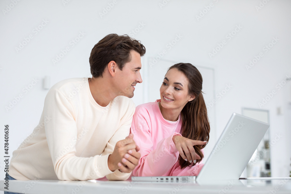 Fototapeta premium Happy young couple using laptop at home together.