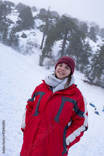 Portrait of happy teenage girl smiling and dressed in warm red coat at snow in winter