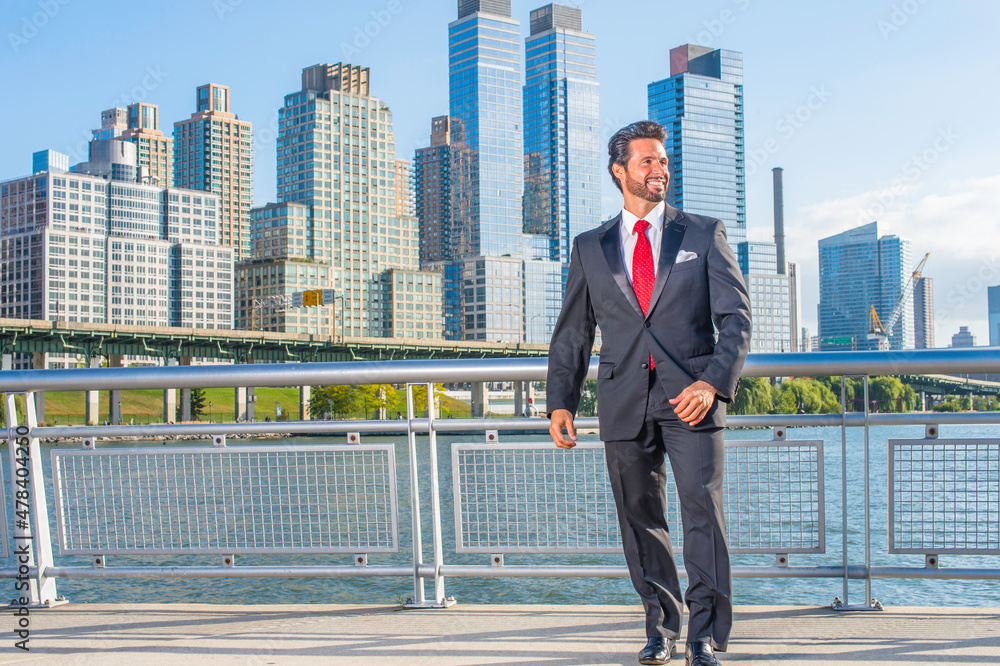Dressing is a black suit and a red tie, a sexy, middle age businessman with mustache and beard is standing in the front of a business district, confidently looking forward.. Dressing is a black suit and a red tie, a sexy, middle age businessman with mustache and beard is standing in the front of a business district, confidently looking forward..