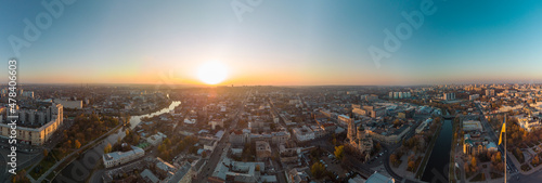 Wide sunny panoramic aerial view above river Lopan embankment near Annunciation Cathedral in Kharkiv, Ukraine. Flag of Ukraine with epic autumn cityscape, city streets