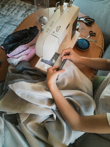 Top view of a sewing machine and hands of a young girl