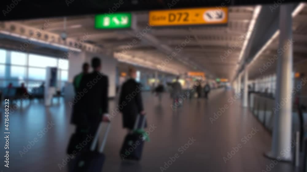 Defocused shot of passengers and stewardess walk in international Airport. People walking for take flight in terminal lounge gates. European airports. Blurred background in the scene Defocused shot of passengers and stewardess walk in international Airport. People walking for take flight in terminal lounge gates. European airports. Blurred background in the scene