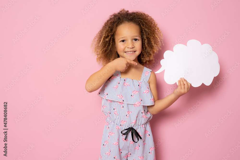 Smiling little girl in summer clothes showing paper cloud standing isolated over pink background. Smiling little girl in summer clothes showing paper cloud standing isolated over pink background.