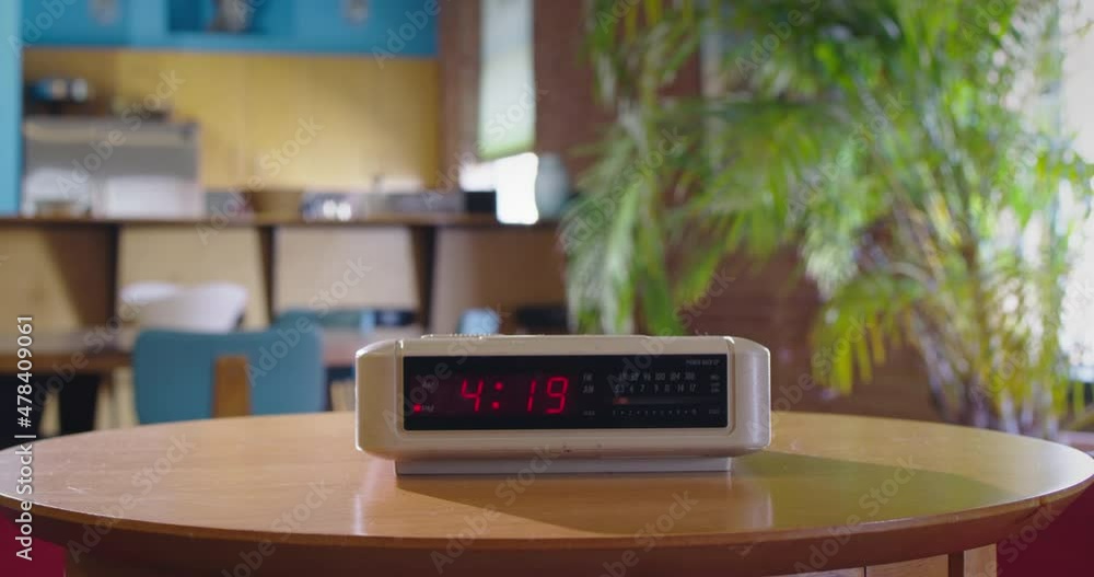 Detail of vintage digital alarm clock sitting on side table as time passes from 4:19 to 4:20 