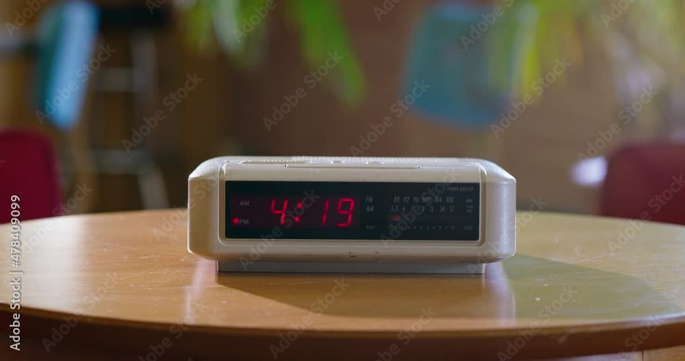 Detail of vintage digital alarm clock sitting on side table as time passes from 4:19 to 4:20 