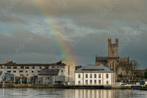 Rainbow in the sky over Limerick City District Court building and St Mary's Cathedral. Ireland. River Shannon. Popular town landmark and tourist spot. Cloudy sky. Irish luck and stunning nature event.