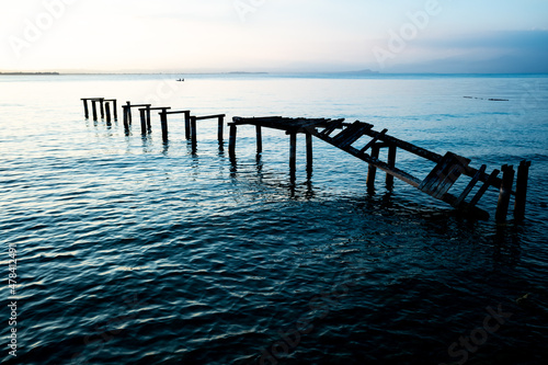 Quadro em tela An old ramshackle pier with broken boards, during a beautiful sunset on a quiet lake