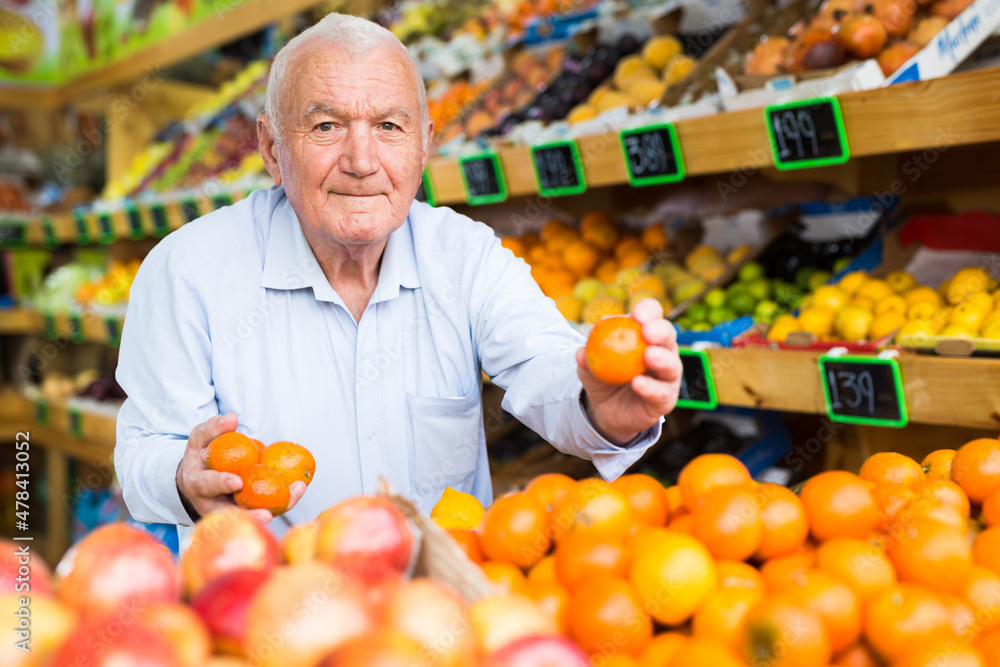 Mature man choosing ripe tangerines in grocery shop