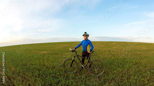 The cyclist rides a bicycle on the green grass on the field. Outdoor sports. Healthy lifestyle. © photosaint