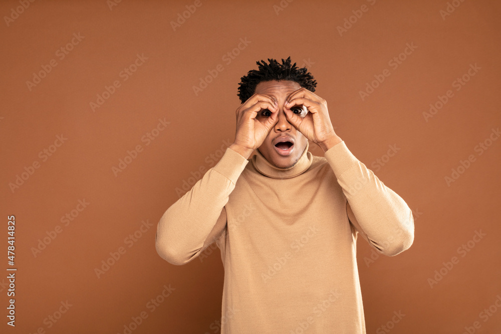 Handsome afro man with shocked expression on his face , looking at camera. Sale concept.