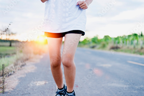 Asian female runner, she runs on the road in the evening sunset.