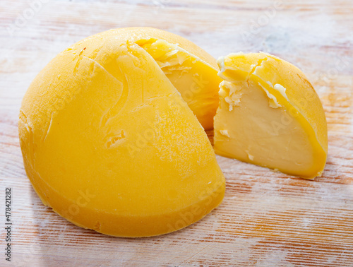 Tetilla cheese (or Perilla) from cow milk with cut piece on wooden surface. Famous cheese from Galicia photo