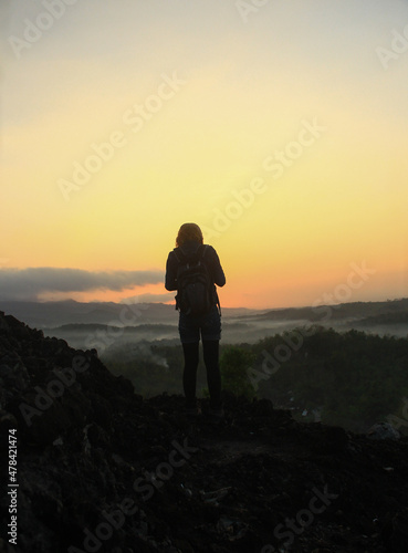 A woman standing at the hill to see beautiful sunrise.