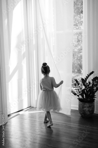Child dressed as a princess looking out the window of a living room