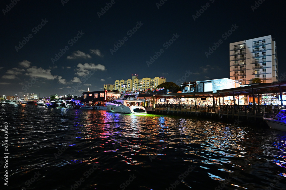 Brightly illuminated office and residential buildings on Miami River in Miami, Florida reflected in water at night.