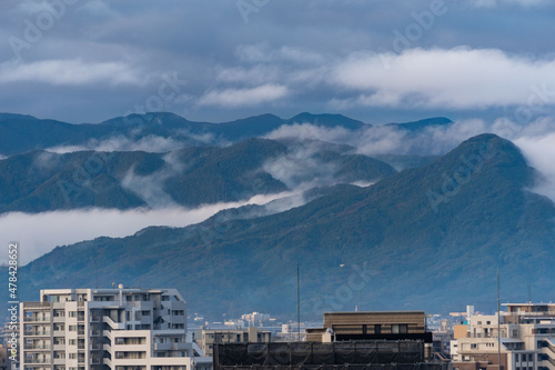clouds is going down around the mountain behind a town. © w108av22