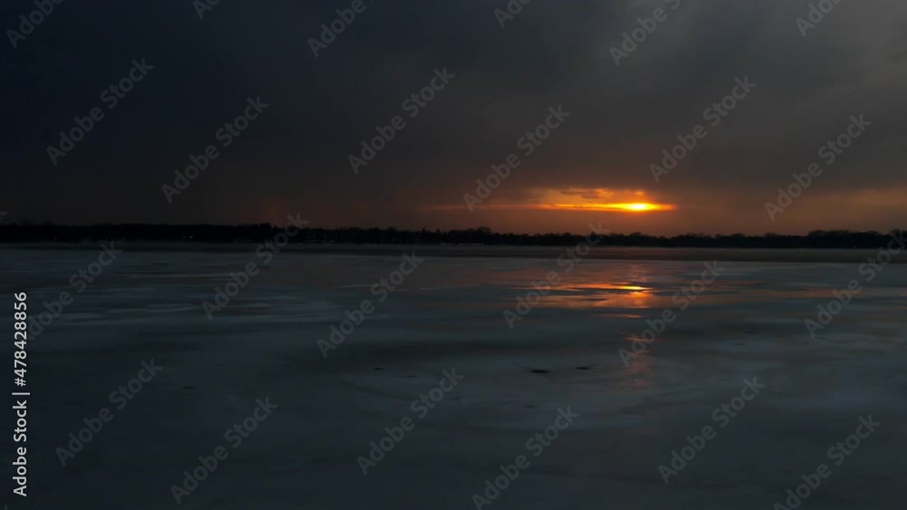 Time lapse of sun setting on the horizon on a cloudy winter afternoon over a frozen lake Time lapse of sun setting on the horizon on a cloudy winter afternoon over a frozen lake