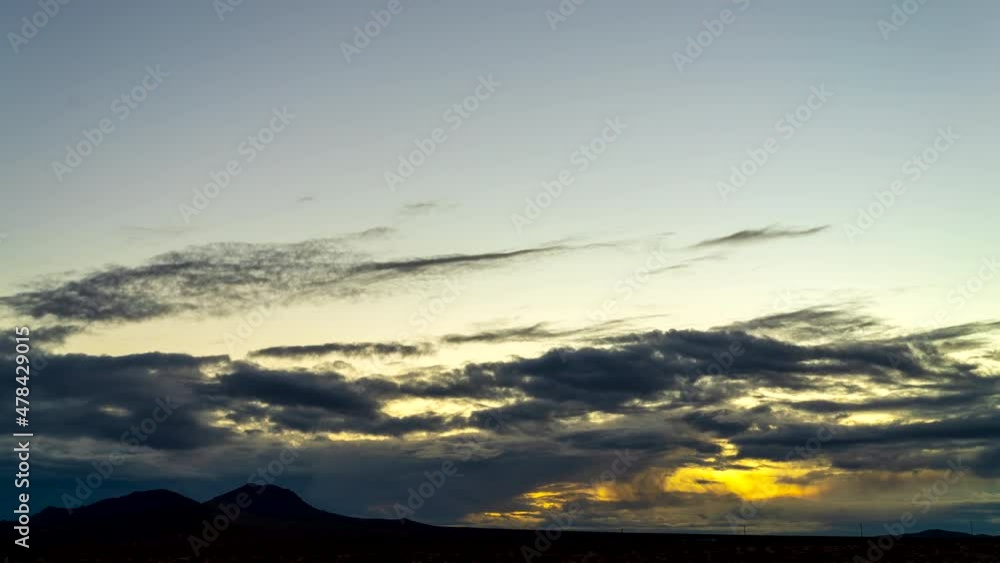 Golden sunrise over the Mojave Desert plains with mountains in silhouette as the cloudscape turns orange - wide angle time lapse Golden sunrise over the Mojave Desert plains with mountains in silhouette as the cloudscape turns orange - wide angle time lapse
