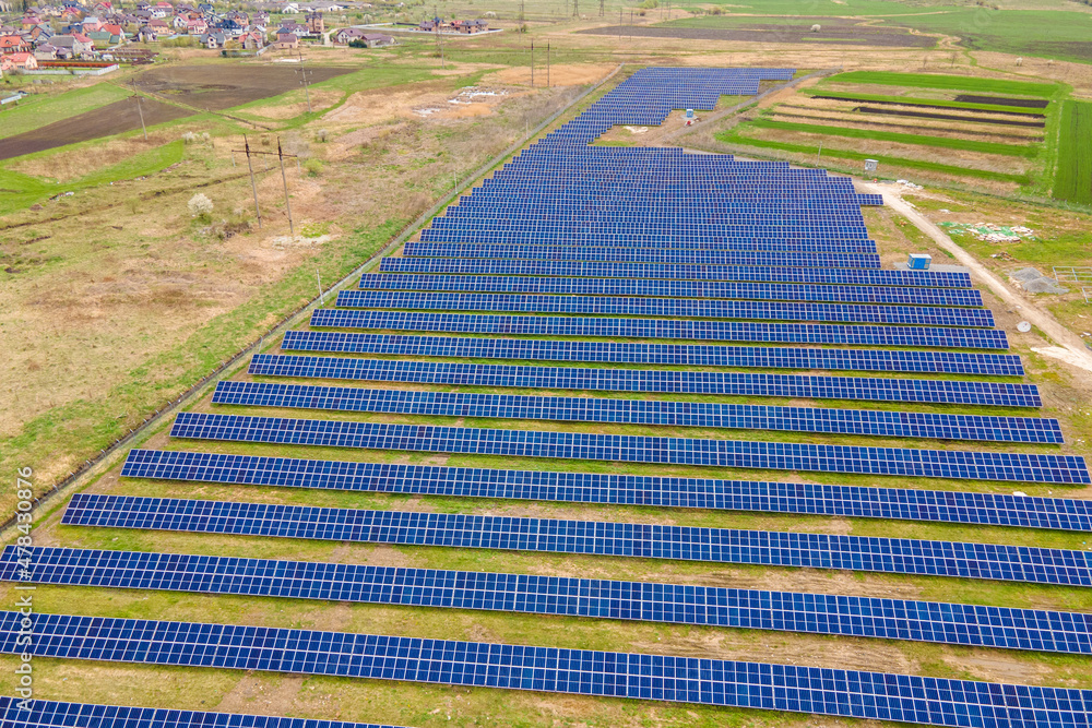 Fototapeta premium Aerial view of big sustainable electric power plant with many rows of solar photovoltaic panels for producing clean ecological electrical energy. Renewable electricity with zero emission concept
