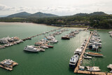 Aerial view of sail boats in marina port in harbor, ocean or bay with blue turquoise seawater in urban city or town, Phuket in travel trip and transportation concept. Top view.
