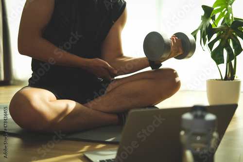 Young man exercising with dumbbells in living room. Fitness and healthy lifestyle concept..