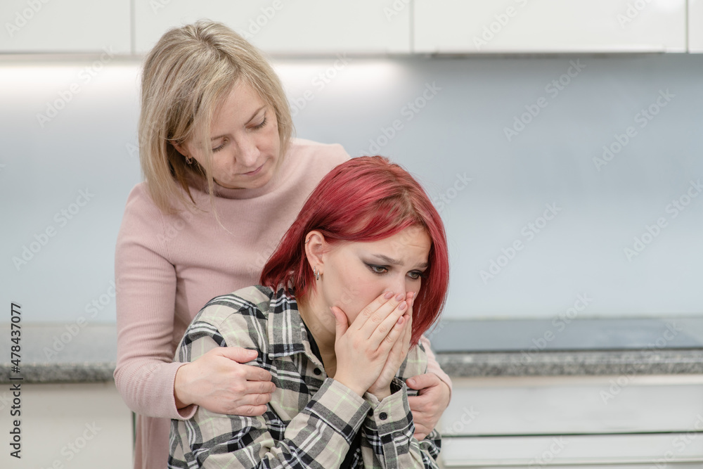Careful mother hugs and calms her crying teen daughter at home. Teenagers problem concept Careful mother hugs and calms her crying teen daughter at home. Teenagers problem concept