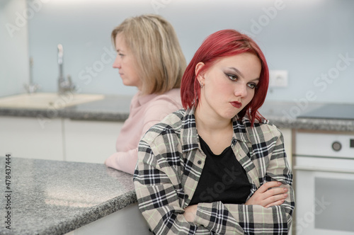 Family conflict. Sad mother and resentful daughter are offended at each other photo
