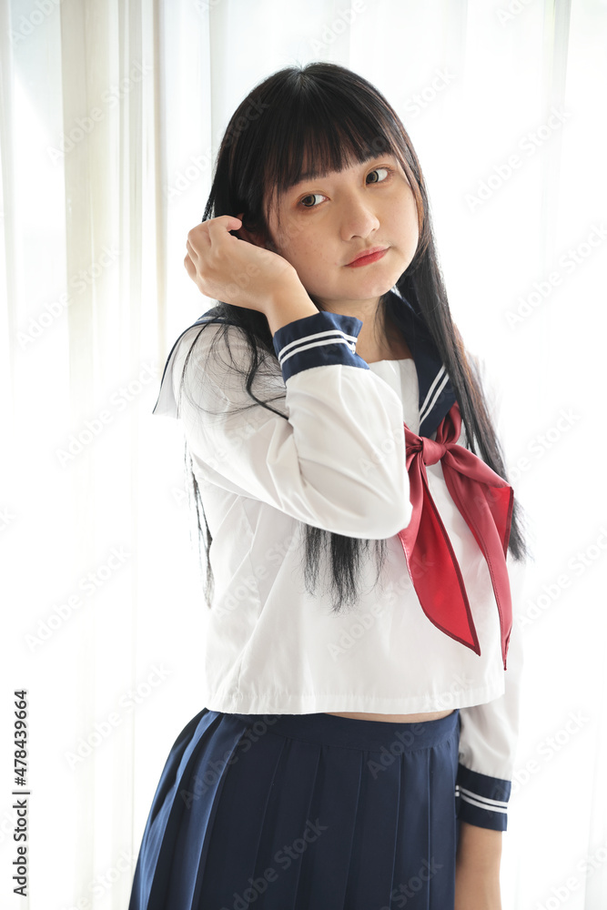Asian female high school student sitting with cosmos flower garden