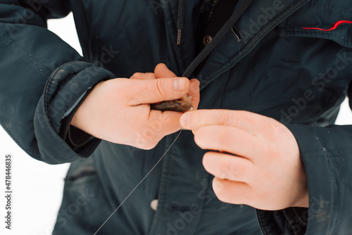 Close-up of man caught fish on hook on winter fishing trip. Fisherman holding small perch outdoors