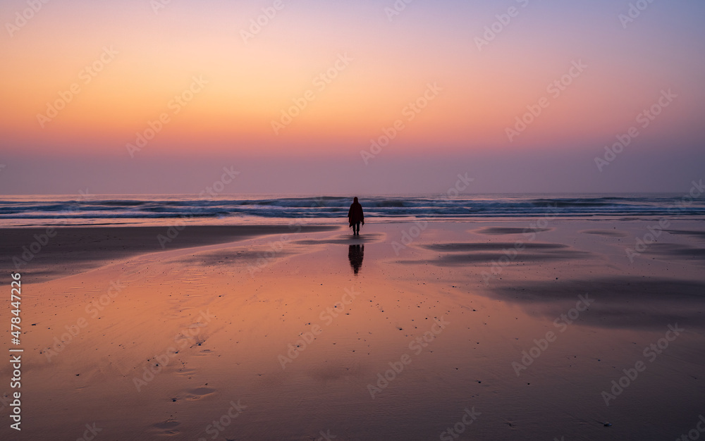 one person standing on the the beach in sunrise