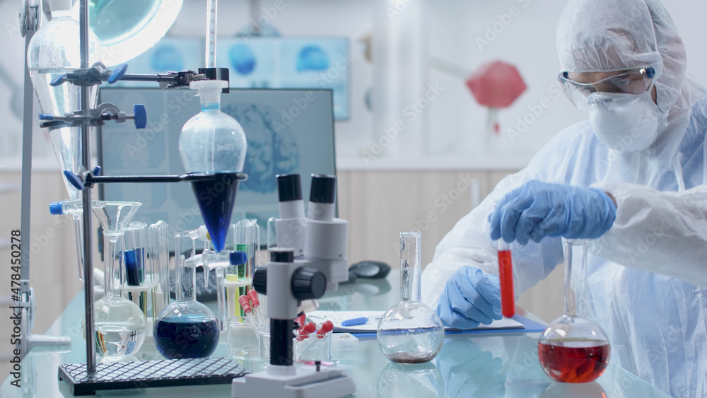 Fototapeta premium Scientist microbiologist doctor working with transparent glassware during biochemistry experiment in laboratory. Doctor man with ppe equipment mixing medical solution developing covid19 vaccine