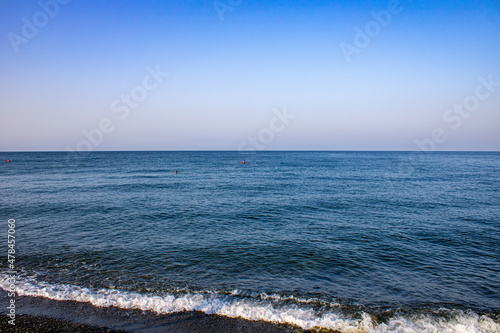 Morning with the calming waves of the Black Sea. On a warm sunny morning with blue cloudless skies. The coast of Sochi, Loo, Russia. photo