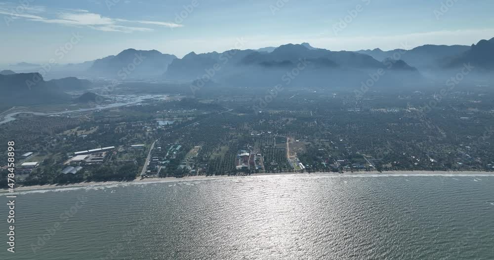 flying above the clean ocean and curve of town with mountain flying above the clean ocean and curve of town with mountain