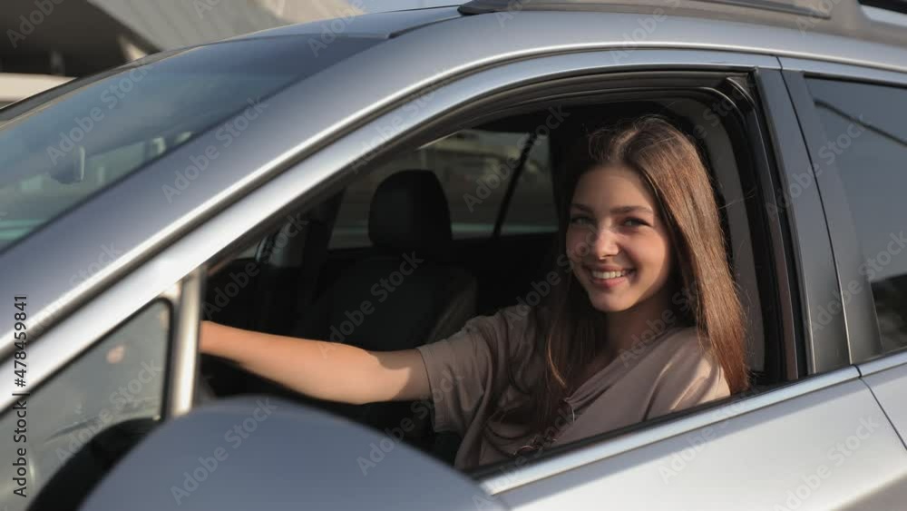 The young woman is looking at the camera and smiling. She is looking out the open window. The wind is blowing her hair. 4K The young woman is looking at the camera and smiling. She is looking out the open window. The wind is blowing her hair. 4K