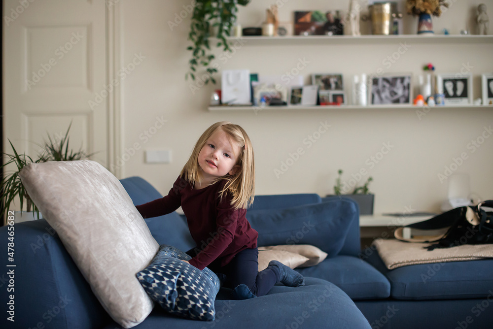 Obraz premium child little girl playing on blue couch at the home