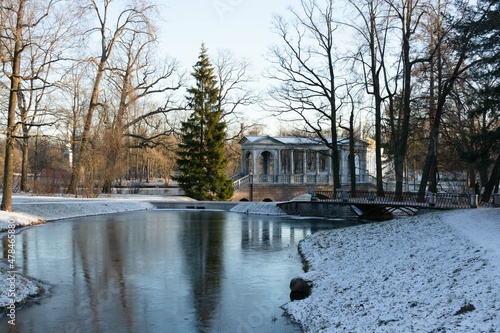 View of the pond of the Catherine Park of St. Petersburg. The marble bridge, the Chesma Column, the Turkish Bath look beautiful on the general plan. A tall green fir tree adorns the picture. photo