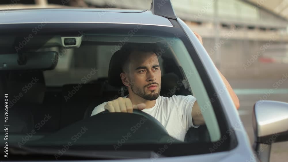 The man is sitting in the car in the driver's seat. He is tired and leaning on the door with his hand. He's holding his head. 4K 50fps The man is sitting in the car in the driver's seat. He is tired and leaning on the door with his hand. He's holding his head. 4K 50fps