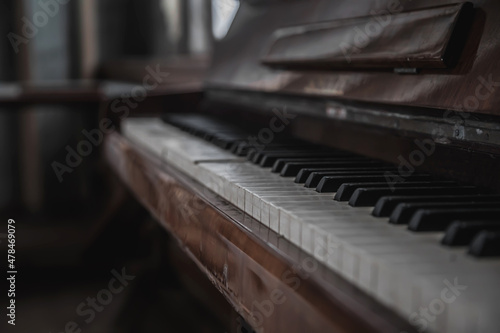 An old piano in an abandoned building. A beautiful musical instrument. Old black abandoned piano with keys.